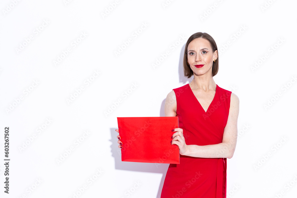 Sensual Portrait of Winsome Positive Confident Caucasian Business Woman in Long Red Dress Demonstrating Red Folder Over White Background Sensual Portrait of Winsome Positive Confident Caucasian Business Woman in Long Red Dress Demonstrating Red Folder Over White Background
