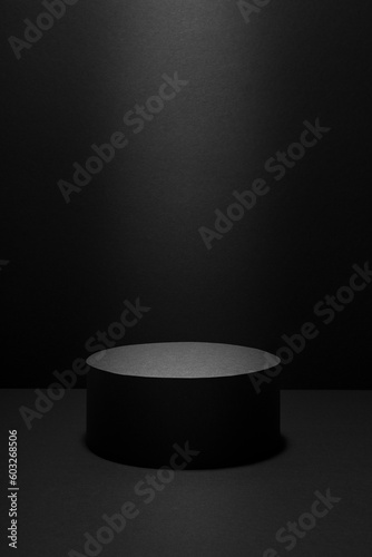 Abstract black scene with one cylinder podium in light beam with light spot template for presentation cosmetic products, goods, advertising, design in gradient, mockup in minimalist style, vertical.