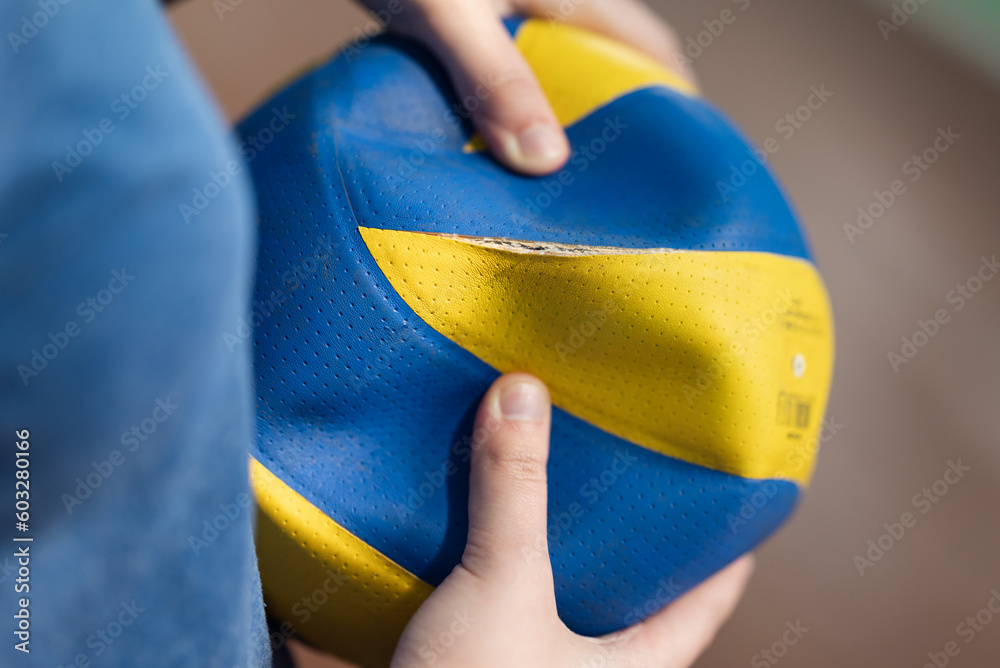 Zdjęcie Stock Old volleyball ball torn on seam in hands of a female player. Ball of a low