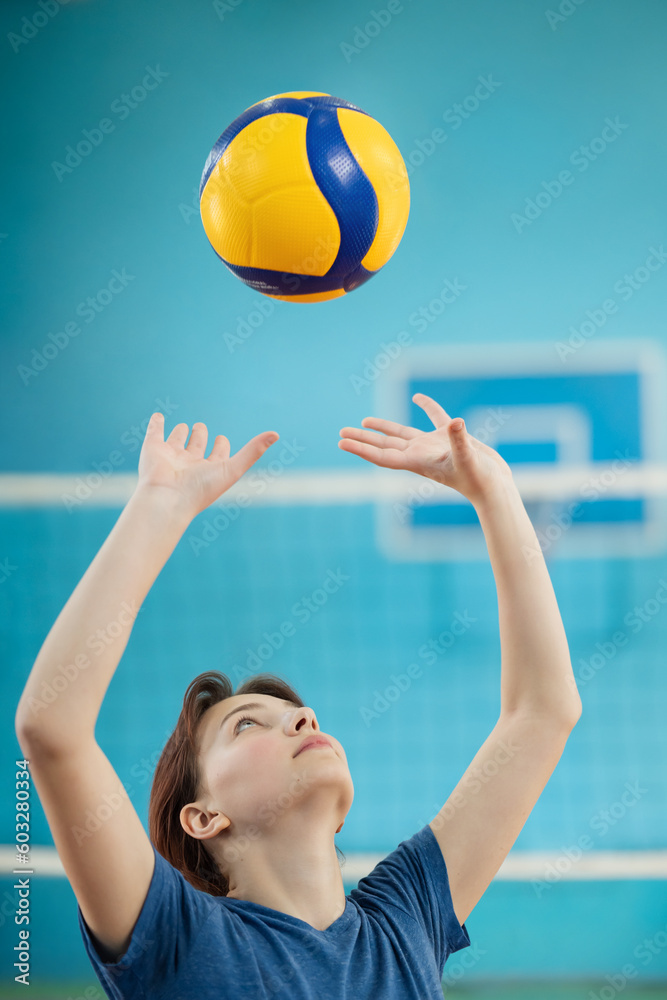 Young girl learning fundamental skills to play volleyball. Photo in action of a girl training to pass and set the volleyball
