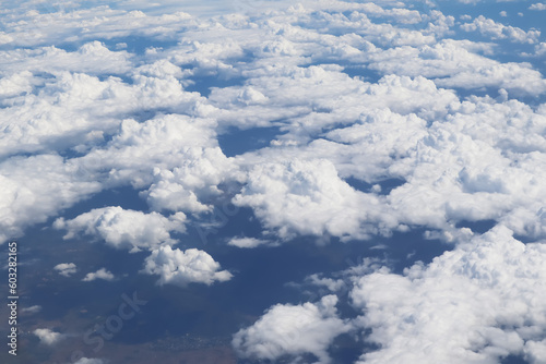 Dramatic aerial view image from aircraft of beautiful groups of white clouds with background of land underneath.Image use for travel industry and airline transportation business. © ekapolsira