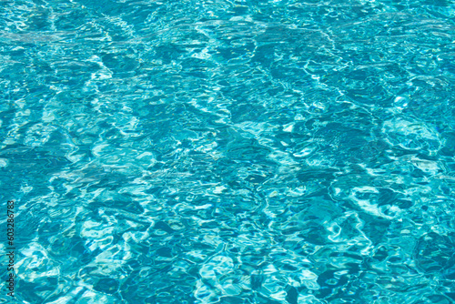 Background of blue water in swimming pool with sun reflection, ripple water wave in pool. Clear water background.