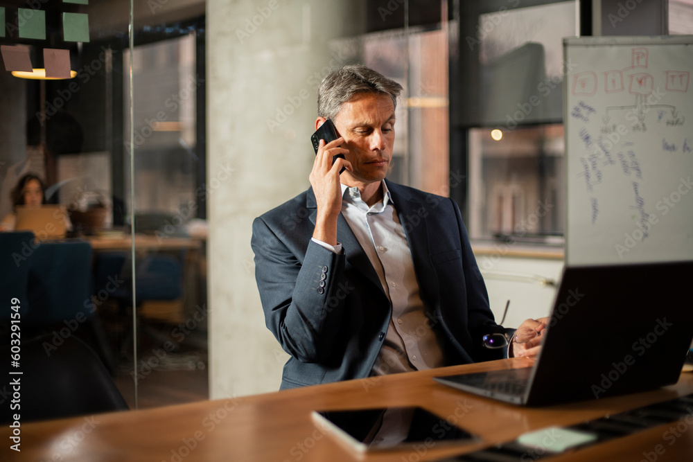 Businessman in office. Handsome man talking on phone at work.. Businessman in office. Handsome man talking on phone at work..