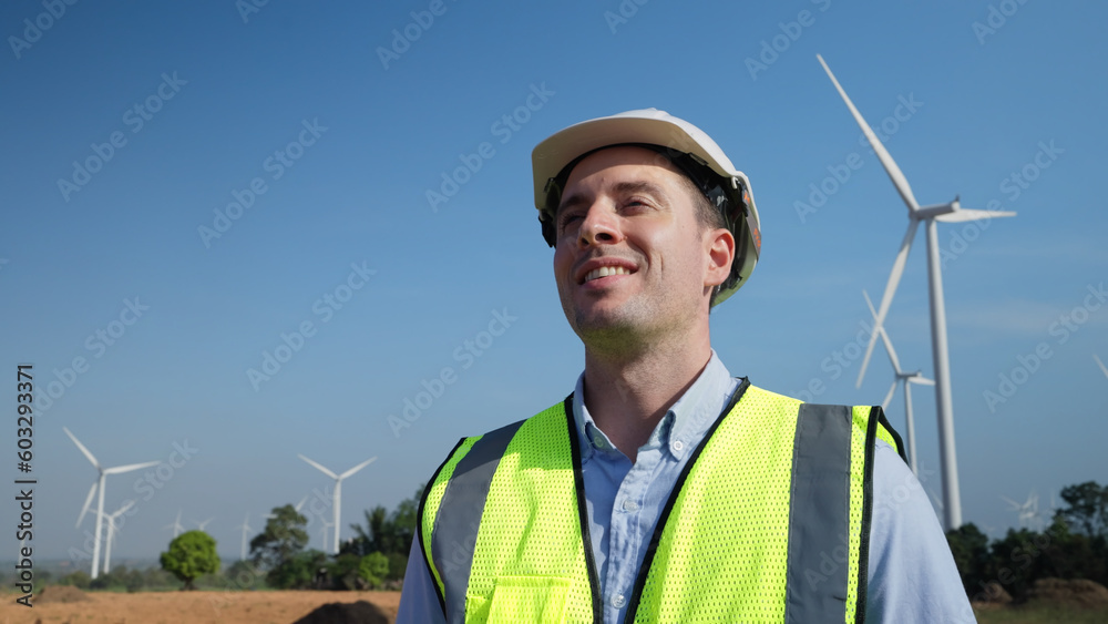 Male engineer standing in a windmill alone. He felt refreshed among the fields of windmills. Male engineer standing in a windmill alone. He felt refreshed among the fields of windmills.
