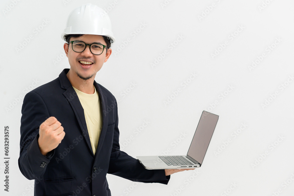 Asian male architect or engineer wearing white hard hat smiling looking at camera holding laptop doing happy gesture isolated on white background Copy space over a white studio background. Asian male architect or engineer wearing white hard hat smiling looking at camera holding laptop doing happy gesture isolated on white background Copy space over a white studio background.