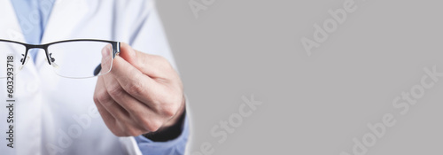 Caucasian professional doctor showing eyeglasses.