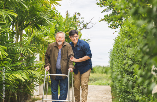 Photos Caregiver is teaching old man to walk with walker, Senior asian father and middl