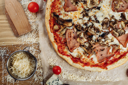 Pizza with chicken cheese and pepperoni, a piece of which is cut and laid out like a pakman, is on a wooden board and a brown background. Cheese spreads flowing streaks photo