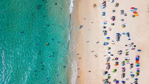Aerial top view Of people crowd relaxing on beach with colorful umbrellas in Phuket, Thailand, Aerial view of sandy beach with tourists swimming in beautiful clear sea water in Thailand.