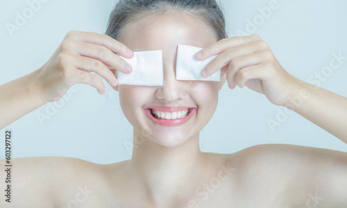 white asian woman Both hands held a cotton ball and covered both eyes. She had a pretty smile. and her teeth are beautiful.