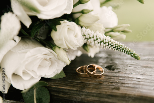 Beautiful wedding bouquet with protea and roses, wedding rings on a forest background