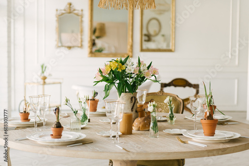Dining table with beautiful setting, glasses and fresh flowers
