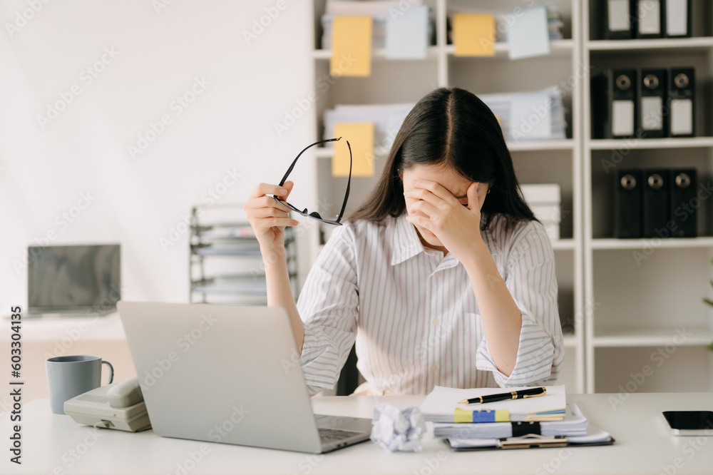 Asian business woman is stressed, bored, and overthinking from working on a tablet at the modern office. Asian business woman is stressed, bored, and overthinking from working on a tablet at the modern office.