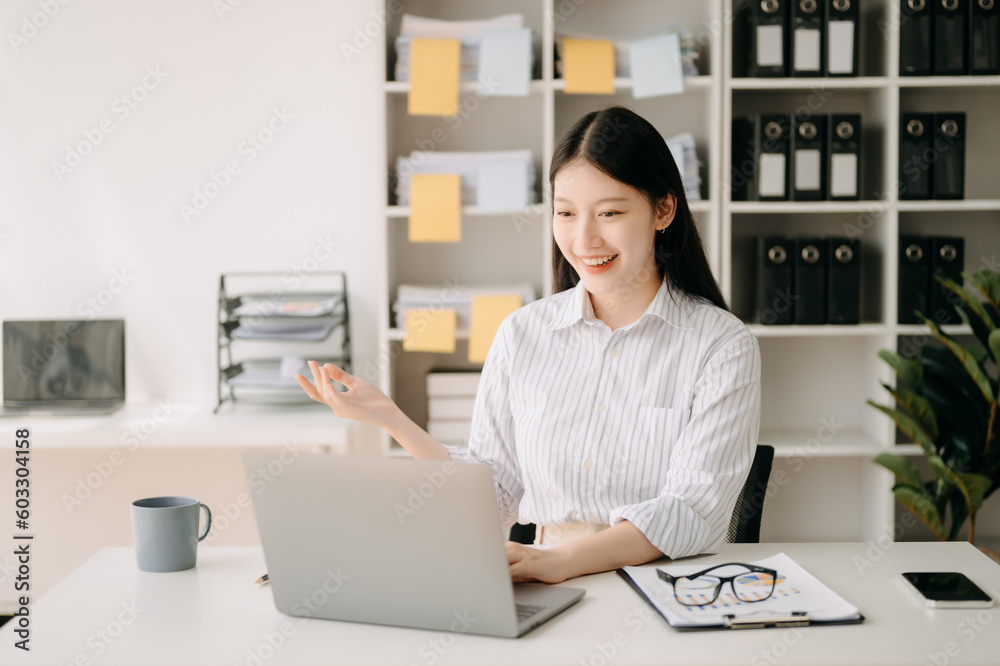 Asian business woman are delighted and happy with the work they do on their tablet, laptop and taking notes at the office..