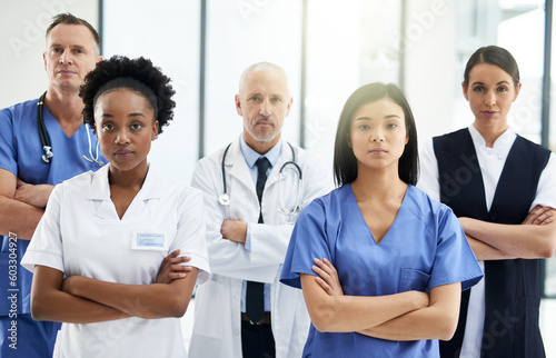 Healthcare, crossed arms and portrait of team of doctors standing in the hallway with confidence. Serious, diversity and group of medical workers in the corridor of a medicare clinic or hospital.