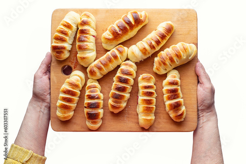 In the hands of a woman, delicious homemade cakes from the oven. Female hands hold a tray with pies on a white background. View from above. Cooking, homemade traditional baking.