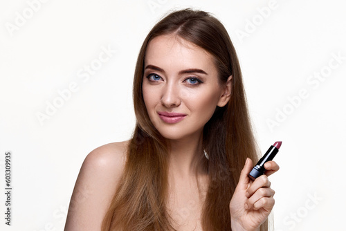 beautiful young smiling woman holding pink lipstick