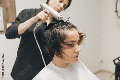 Close-up of the hands of a hairdresser drying women's hair with a hairdryer. short haircut and styling