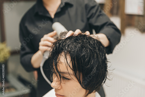 Close-up of the hands of a hairdresser drying women's hair with a hairdryer. short haircut and styling