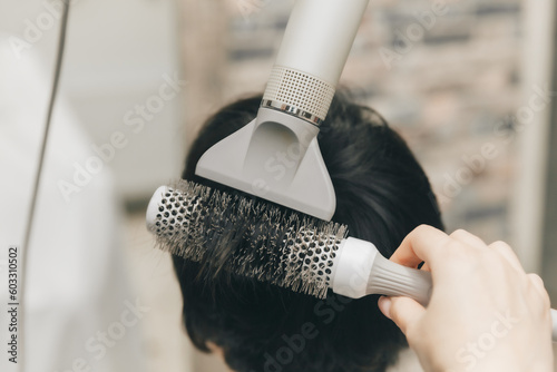 Close-up of the hands of a hairdresser drying women's hair with a hairdryer. short haircut and styling