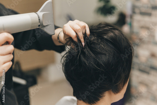 Close-up of the hands of a hairdresser drying women's hair with a hairdryer. short haircut and styling