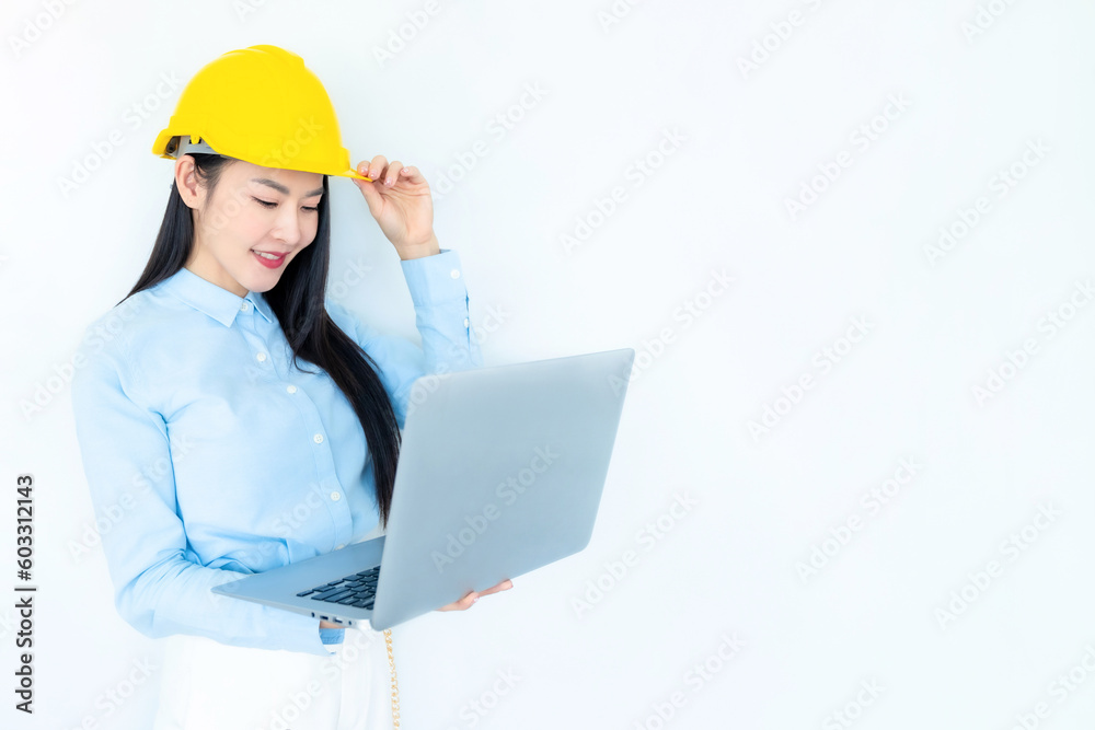 Asian woman architect or construction engineer wear yellow hardhat on white background.Young asian architect woman smiling happy. Asian woman architect looking at laptop. Industry concept. Asian woman architect or construction engineer wear yellow hardhat on white background.Young asian architect woman smiling happy. Asian woman architect looking at laptop. Industry concept.
