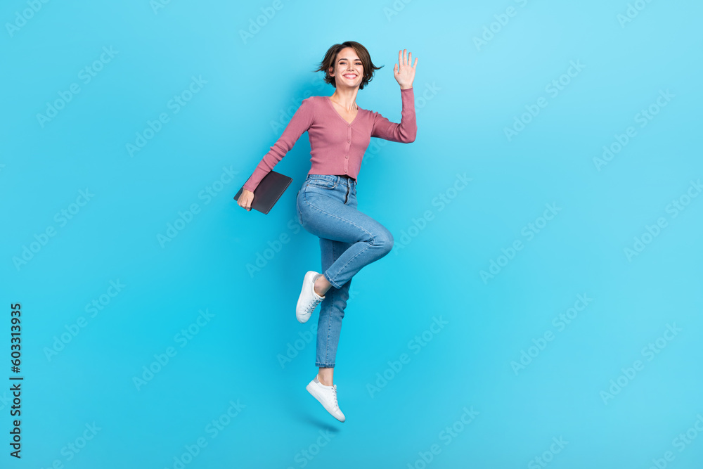 Full size photo of gorgeous cheerful girl hand hold netbook jumping isolated on blue color background
