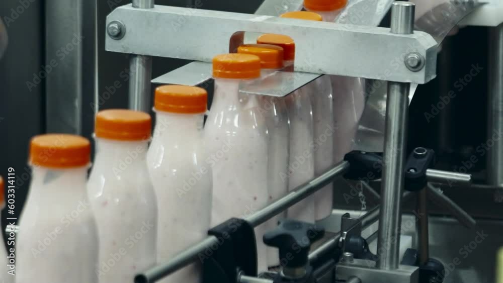 Multiple yogurt bottles are advancing on the production line at a