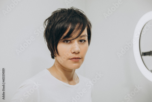 Close up portrait of beautiful young asian girl with black short pixie haircut looking directly at camera photo
