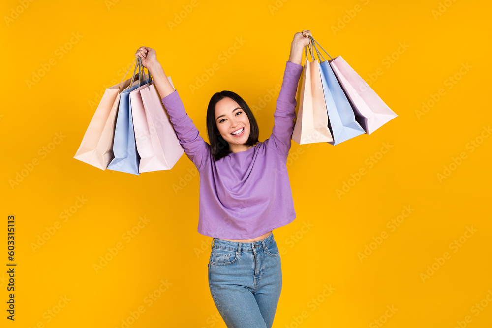 Photo of funky cheerful woman wear violet shirt rising shoppers smiling isolated yellow color background