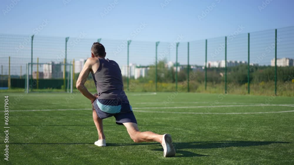Back view Caucasian man doing lunges in slow motion warming up exercising outdoors. Tracking shot of motivated adult sportsman training on sunny spring summer day Back view Caucasian man doing lunges in slow motion warming up exercising outdoors. Tracking shot of motivated adult sportsman training on sunny spring summer day