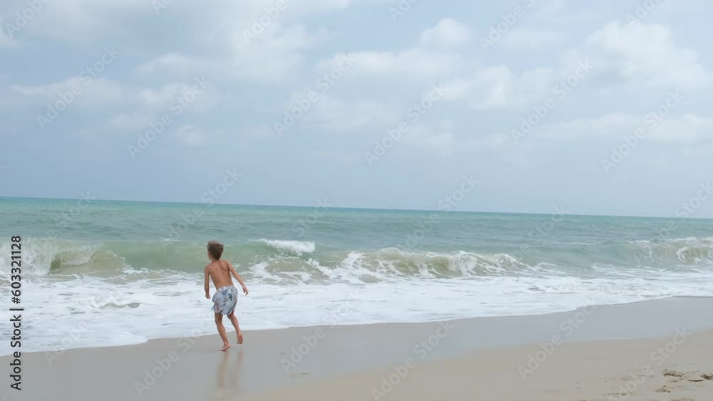 happy boy running away from the sea waves, holidays at sea happy boy running away from the sea waves, holidays at sea