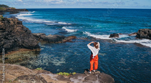 Lonely woman dressed light summer clothes enjoying Indian ocean view with strong surf on cliff at Gris Gris viewpoint extreme south of Mauritius island. Traveling around the world concept image. photo