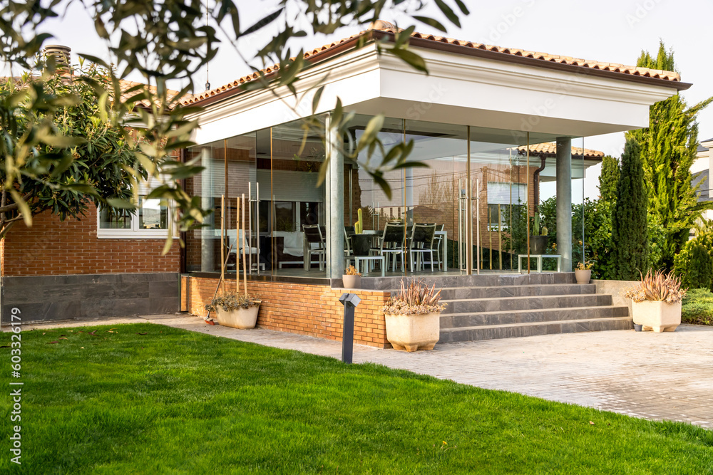 Private family house entry with porch and garden. Side view of the porch and green grass Private family house entry with porch and garden. Side view of the porch and green grass