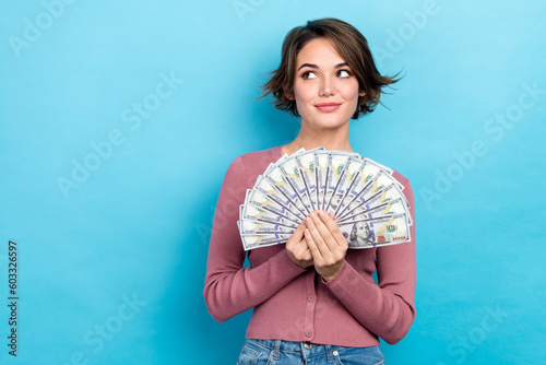 Photo of shiny dreamy lady wear pink cardigan holding money fan looking empty space isolated blue color background
