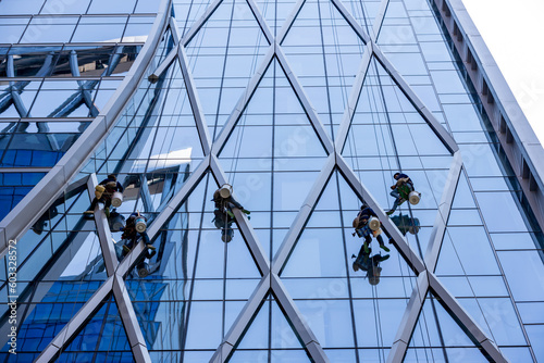 Fotografie Workers washing windows of the skyscraper building