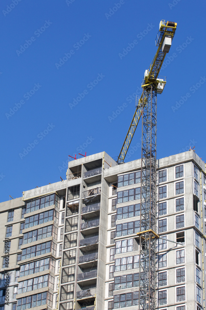 Construction site. Reinforced concrete frame of a multi-storey building and construction cranes. The final stage of construction. Against the background of the blue sky.