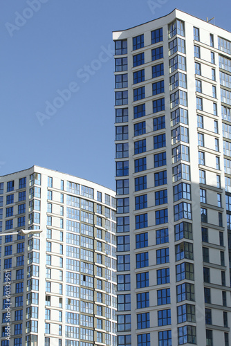 Modern high-rise buildings made of concrete and glass. Construction site. The final stage of construction. Against the background of the blue sky.