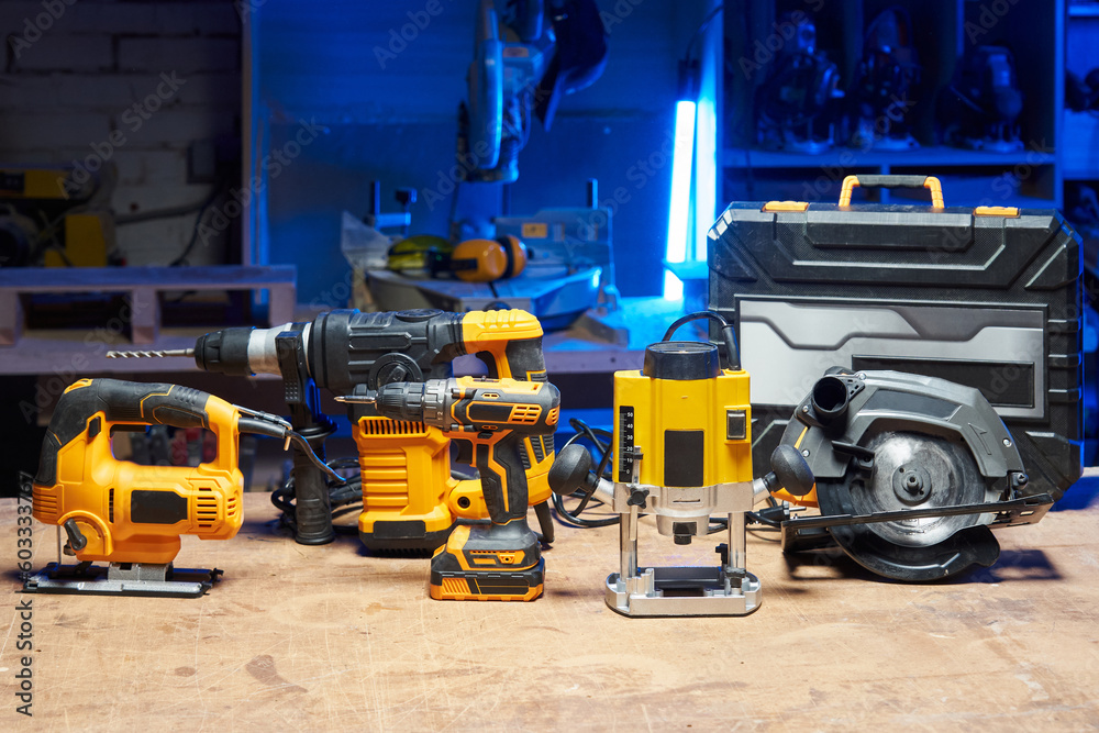Fototapeta premium A set of tools and electrical devices is on the table. circular saw, screwdriver, perforator, drill, jigsaw, router in a carpentry workshop