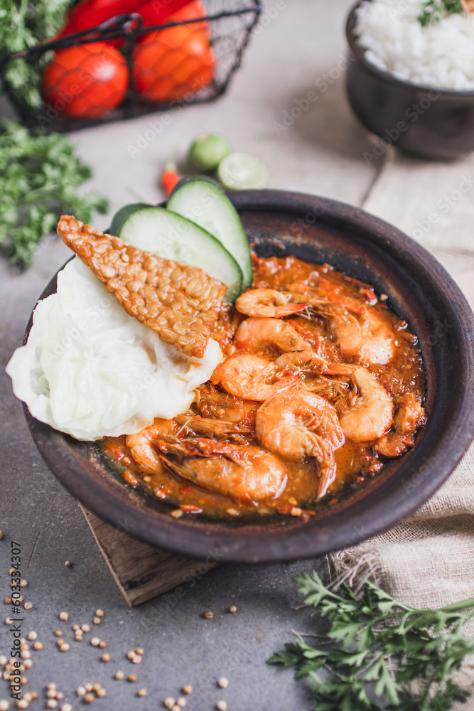 Udang sambal gami or spicy prawn is Traditional food from Indonesia. served on plate with a bowl of rice and vegetables. Isolated gray background Udang sambal gami or spicy prawn is Traditional food from Indonesia. served on plate with a bowl of rice and vegetables. Isolated gray background