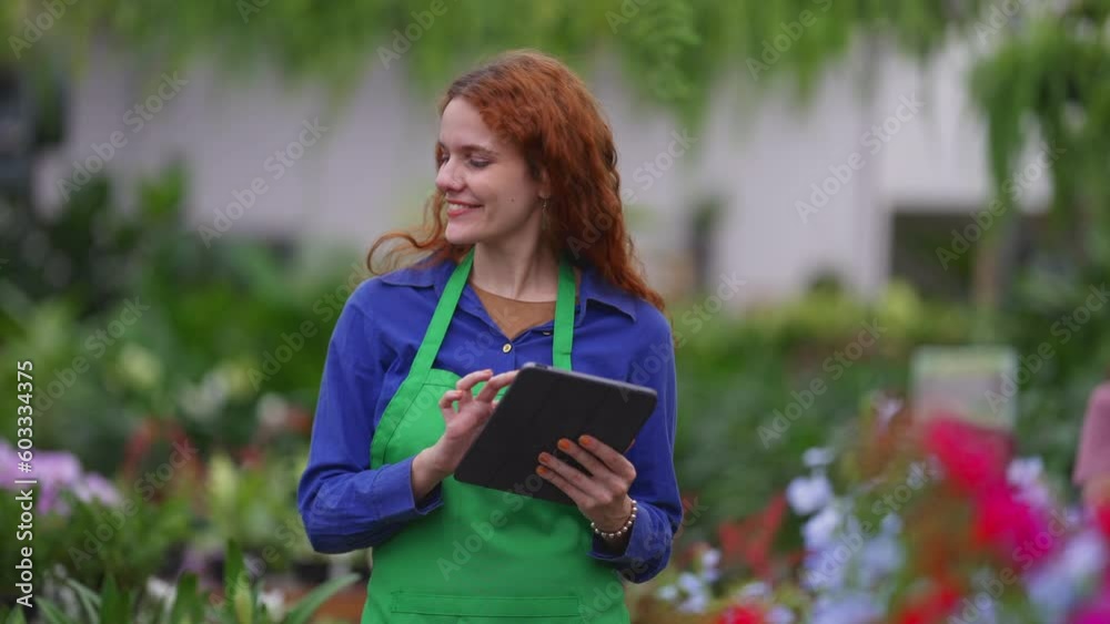 Happy Florist Redhead young entrepreneur woman holding tablet and smiling at camera standing inside business retail store. Happy Florist Redhead young entrepreneur woman holding tablet and smiling at camera standing inside business retail store.