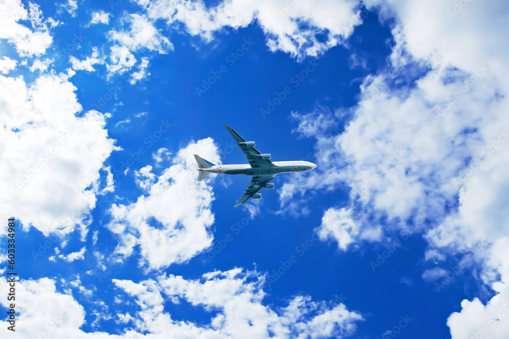 Airplane in the blue sky with clouds from below, high flying passenger ...