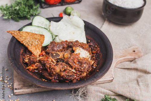 Iga sapi sambal gami or spicy 
beef ribs is Traditional food from Indonesia. served on plate with a bowl of rice and vegetables. Isolated gray background
