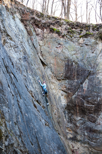 rock climber climbs an almost vertical wall of rock with a safety rope