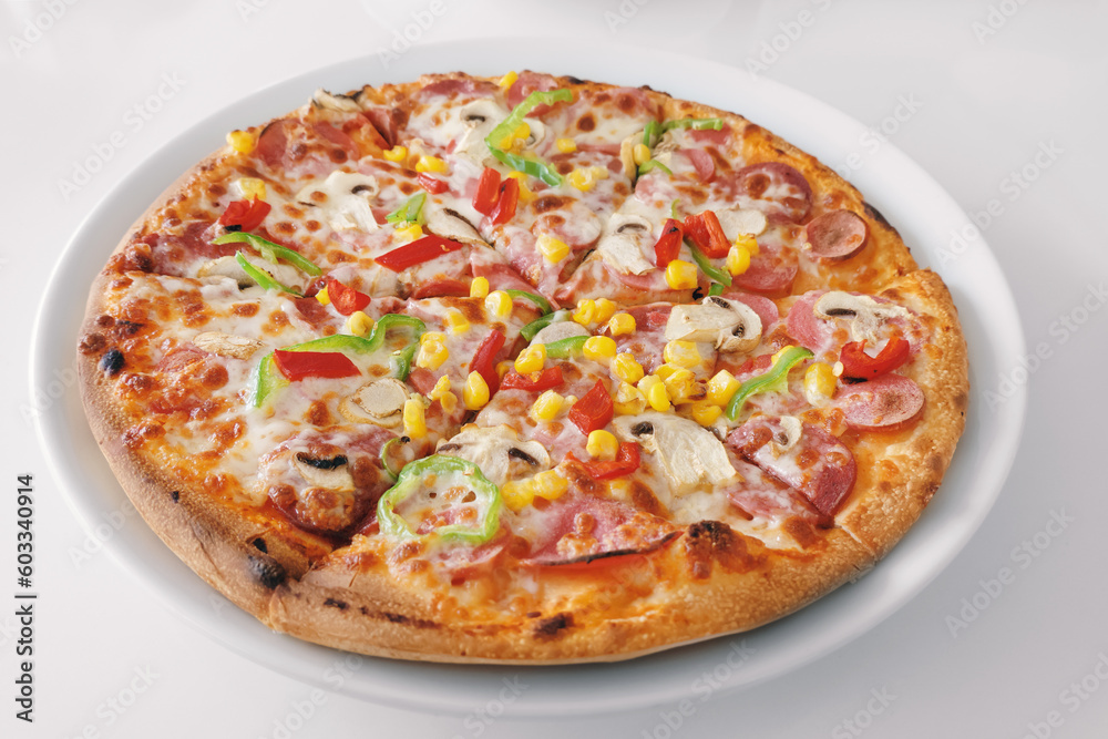 Pizza with mushrooms, sweet peppers, corn, pepperoni and cheese on white table