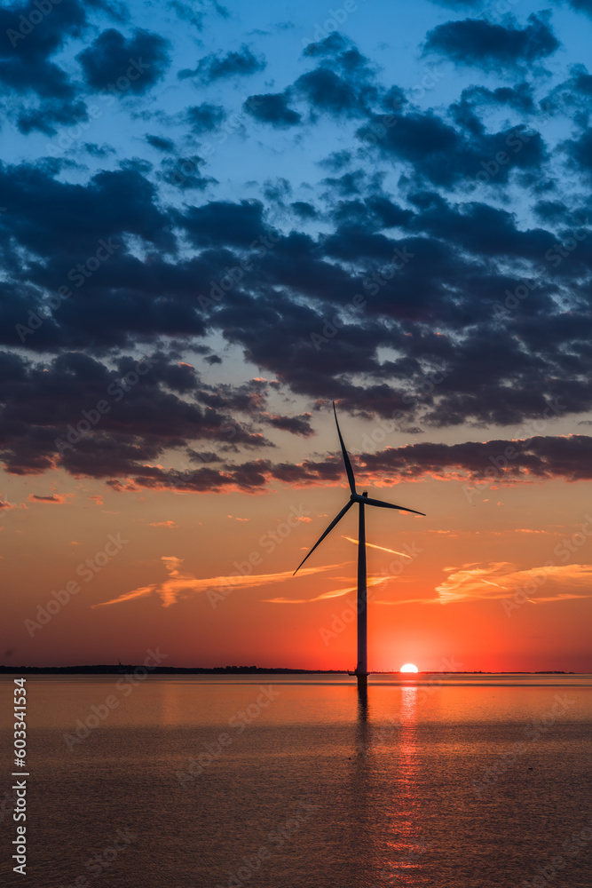 Obraz premium Wind turbine in the sea in the warm sunset light