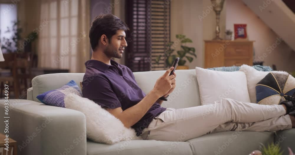 Relaxed Man Resting on Sofa, Browsing Smartphone for Work and Leisure. Researching New Online Shopping Ideas, Staying Updated on Social Media, and Connecting with Friends Online. Slow Moption Relaxed Man Resting on Sofa, Browsing Smartphone for Work and Leisure. Researching New Online Shopping Ideas, Staying Updated on Social Media, and Connecting with Friends Online. Slow Moption
