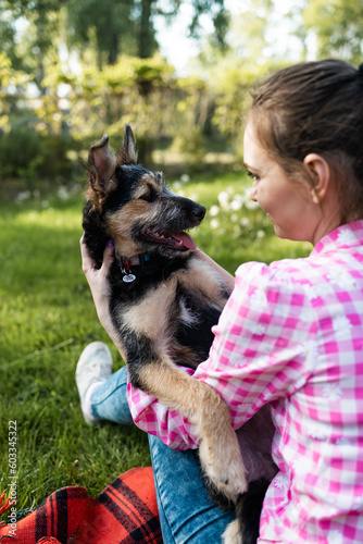 Beautiful young woman playing with her young dog in the park outdoors. Life style portrait. © Mykola