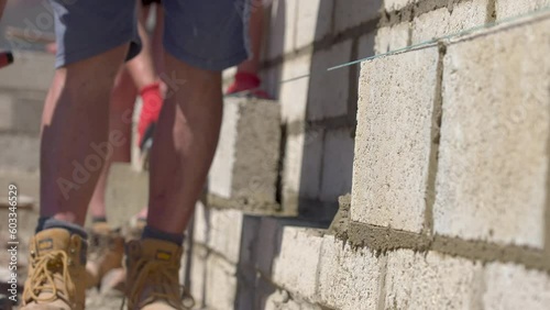 UK - a bricklayer adds mortar to a wall with his trowel