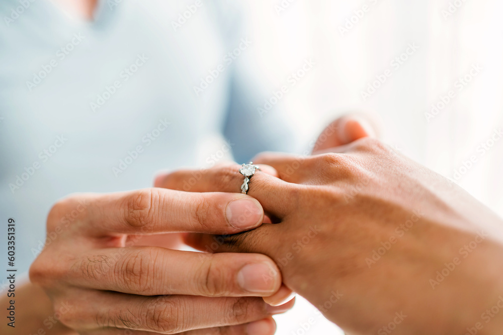 Close-up hands of gay couple, proposing and marriage surprise wear a wedding ring in the living room at home. Gay men proposal engagement concept. Surprised partner is very happy. Relationship goal. Close-up hands of gay couple, proposing and marriage surprise wear a wedding ring in the living room at home. Gay men proposal engagement concept. Surprised partner is very happy. Relationship goal.